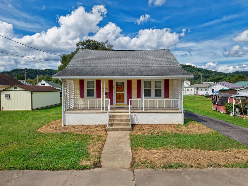 Single-story home with red shutters, a covered porch, and a straight concrete walkway.