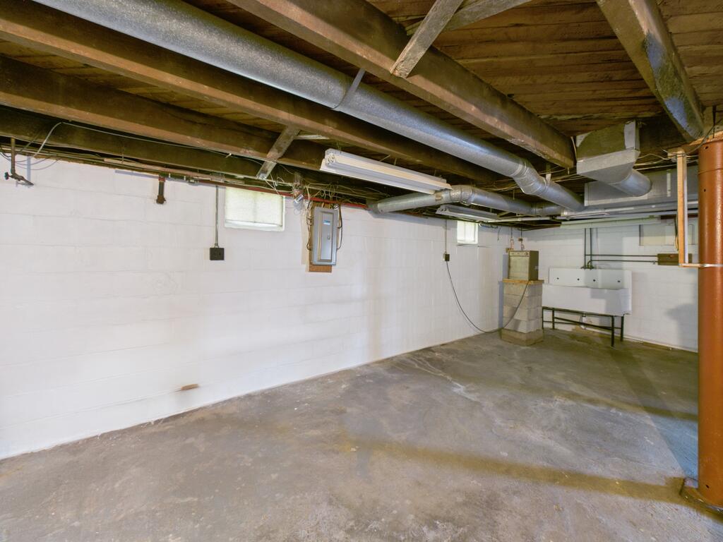 Unfinished basement with exposed ceiling joists and ductwork above a concrete floor.