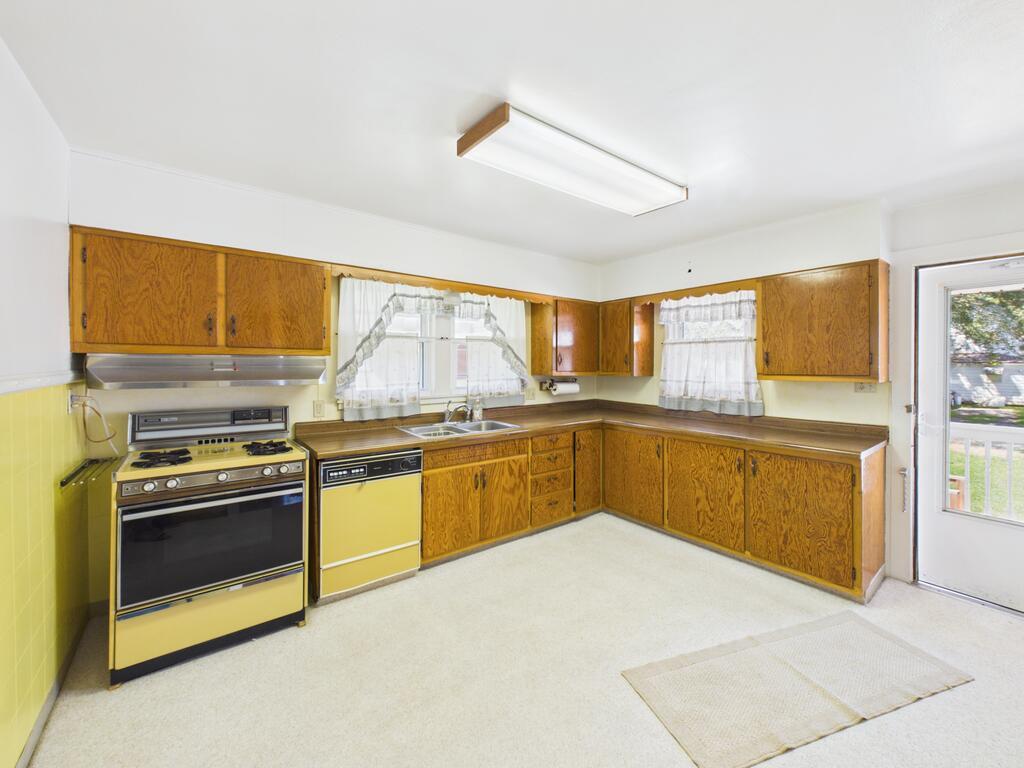 Kitchen with wood-grain cabinets, yellow appliances, a corner sink, and a glass exterior door.