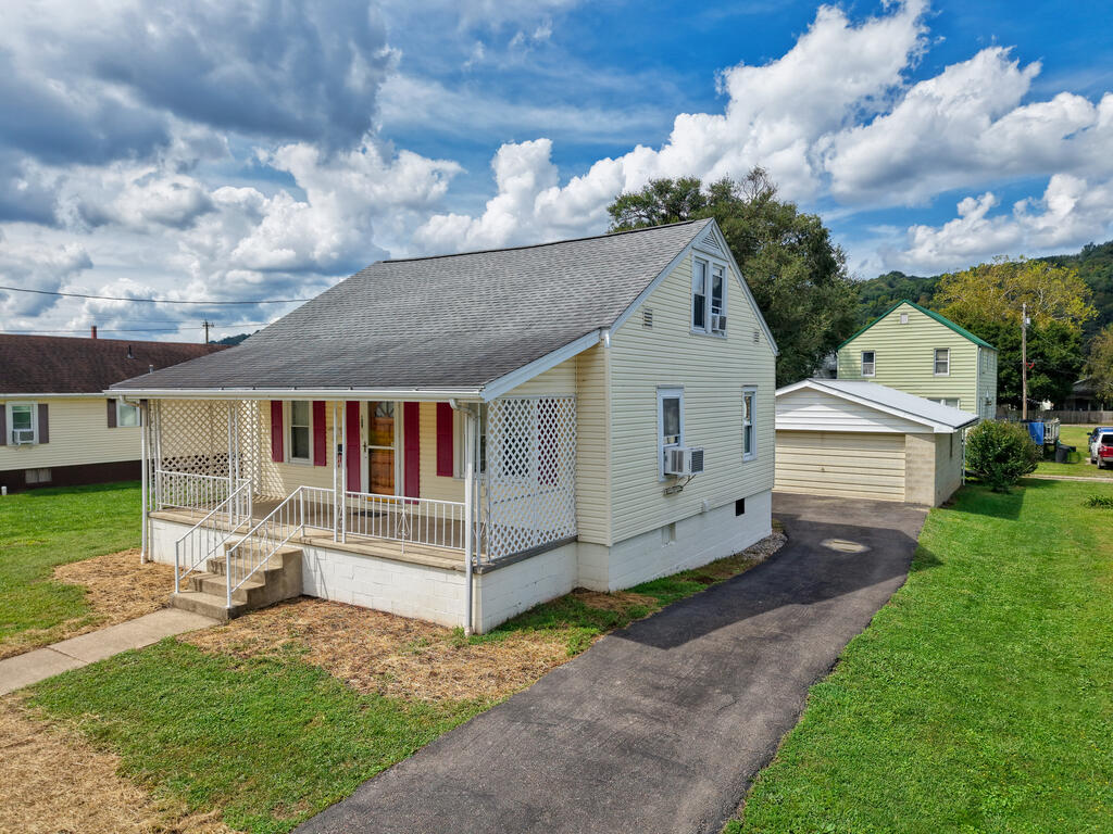 Light-colored house with a lattice-covered front porch and driveway leading to a detached garage.