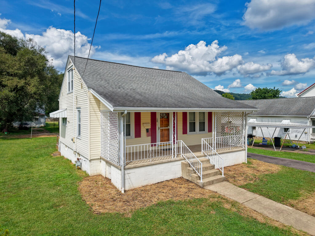 Cream-sided house with a covered porch, red shutters, white lattice, and concrete front steps.