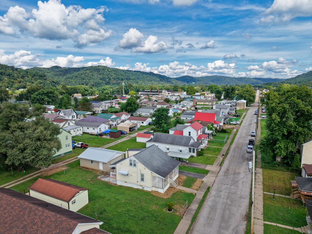 Aerial view of a residential neighborhood, with a straight street and wooded hills in the distance.