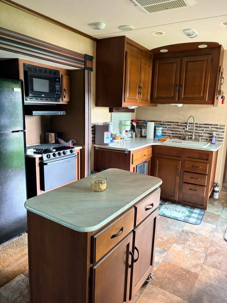 Compact kitchen with dark wood cabinets and a central island with a pale countertop.