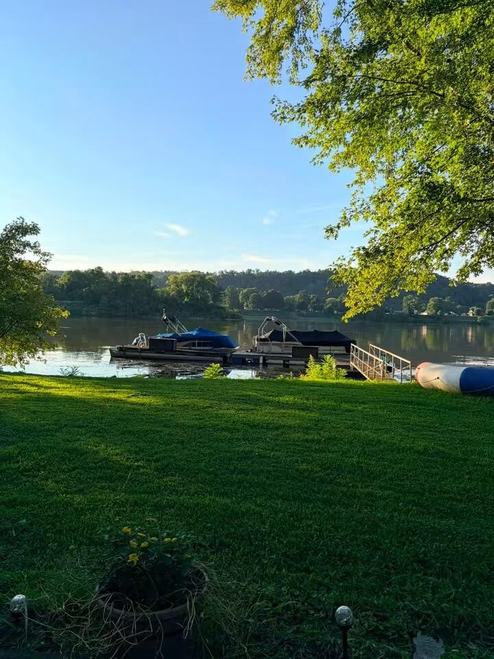 Riverfront lot with a grassy lawn, dock, and boats beside the water.