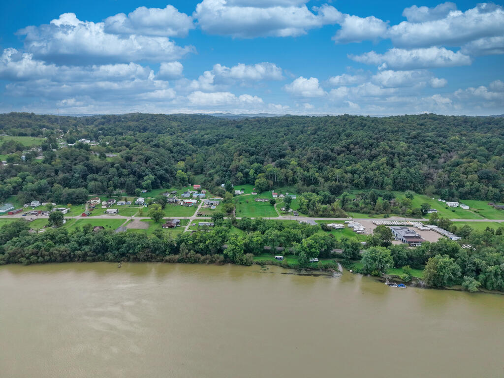 Aerial view across a river toward a small community and densely wooded hills.