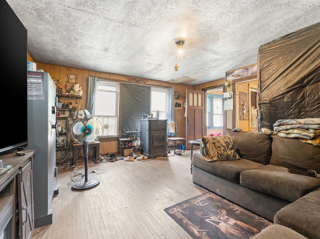 Living room with a gray sectional, wood-burning stove, and standing fan.