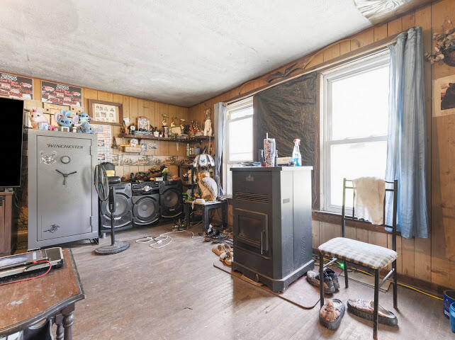 Wood-paneled room with a Winchester safe, audio equipment, a freestanding heater, and two windows.
