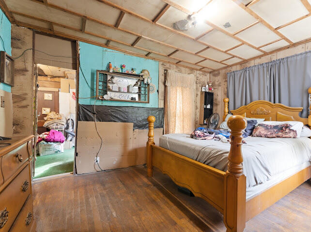 Bedroom with a large wooden bed and exposed ceiling framing.