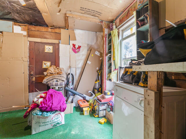 Cluttered garage with storage boxes, tools, a workbench, and a window.