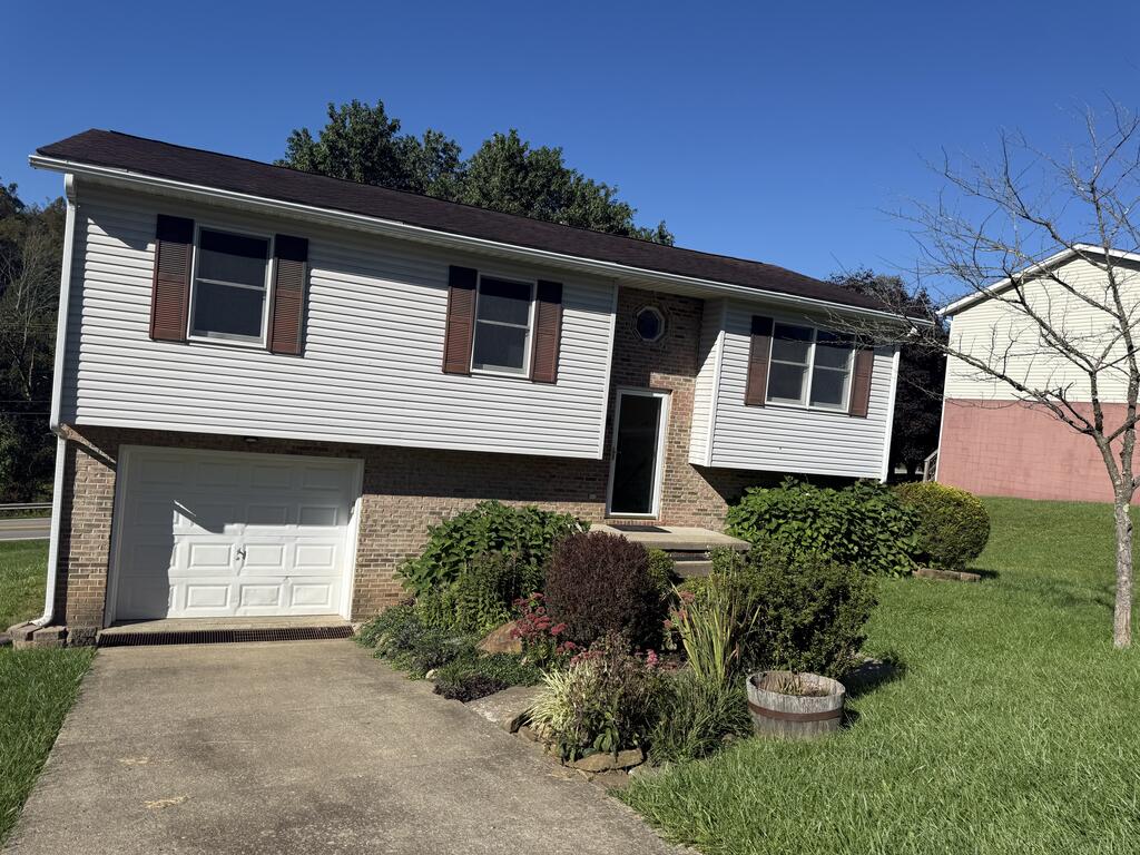 Split-level house with an attached garage, brick accents, and landscaped front yard.