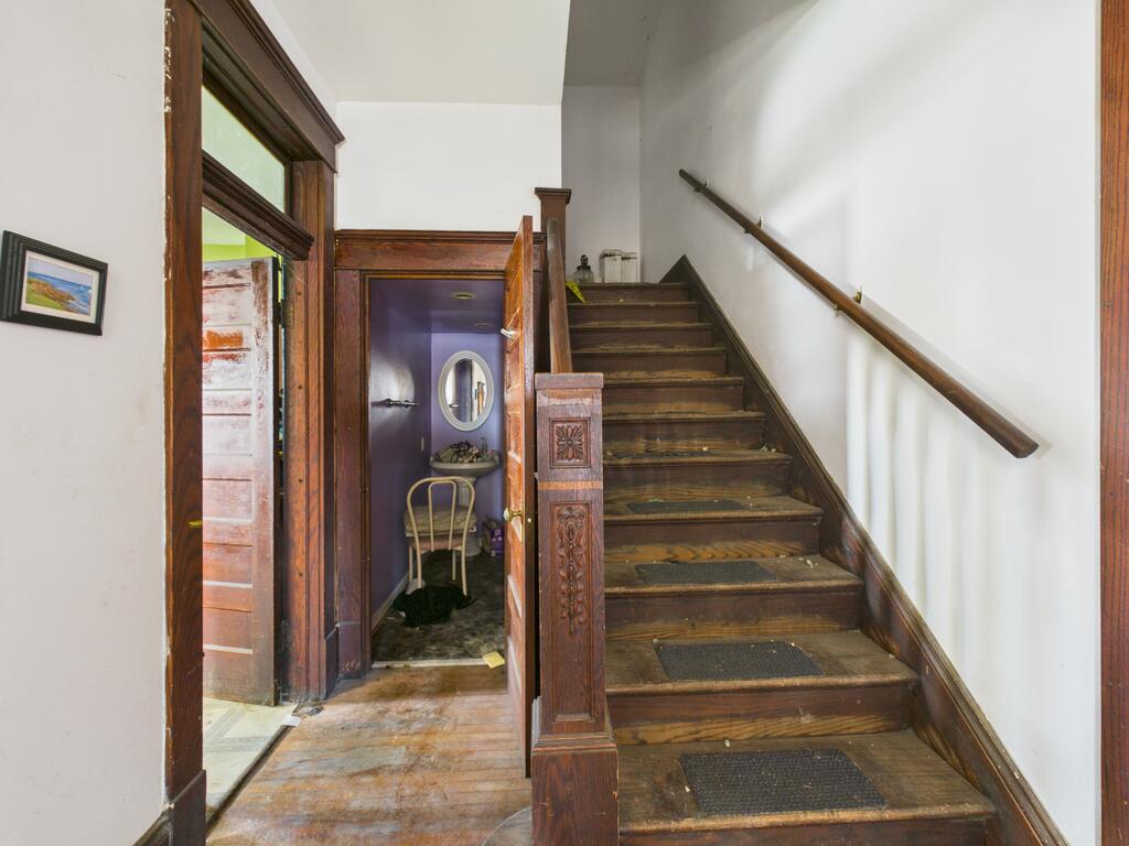 Entry hall with a carved dark wood staircase and an open doorway to a purple room.