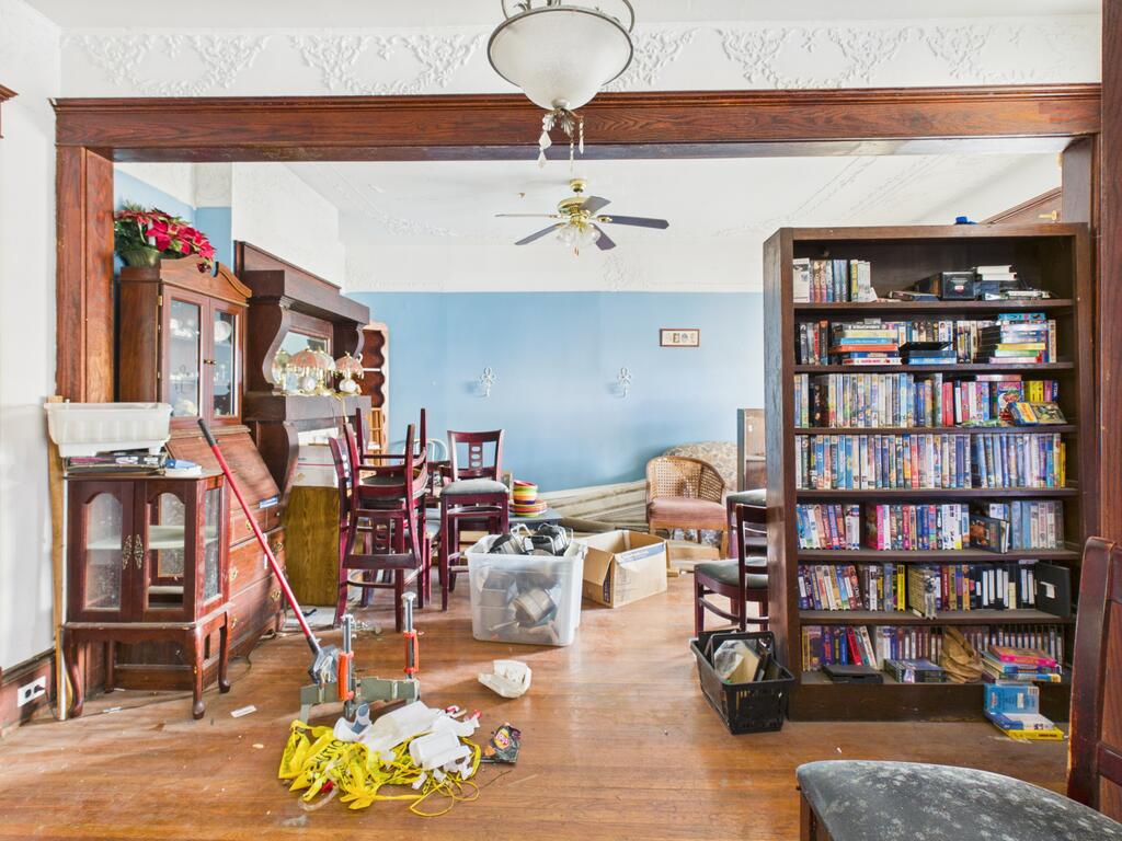 Interior room with ornate wood trim, blue walls, dining furniture, and a bookcase filled with DVDs.