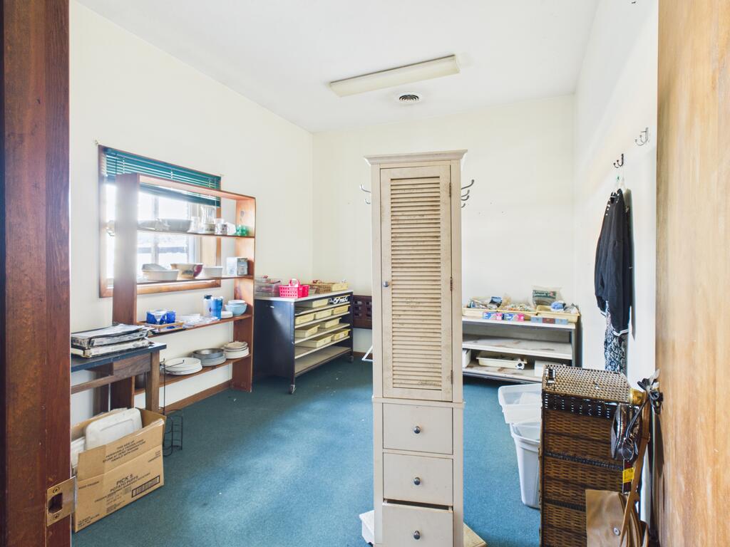 Interior room with blue flooring, display shelves, counters, and a central louvered cabinet.