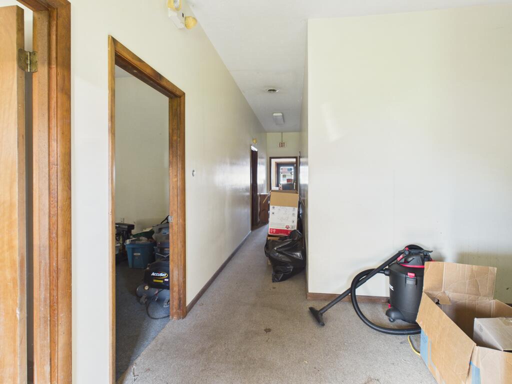 Interior hallway with wood-trimmed doorways, carpet, a shop vacuum and cardboard boxes.