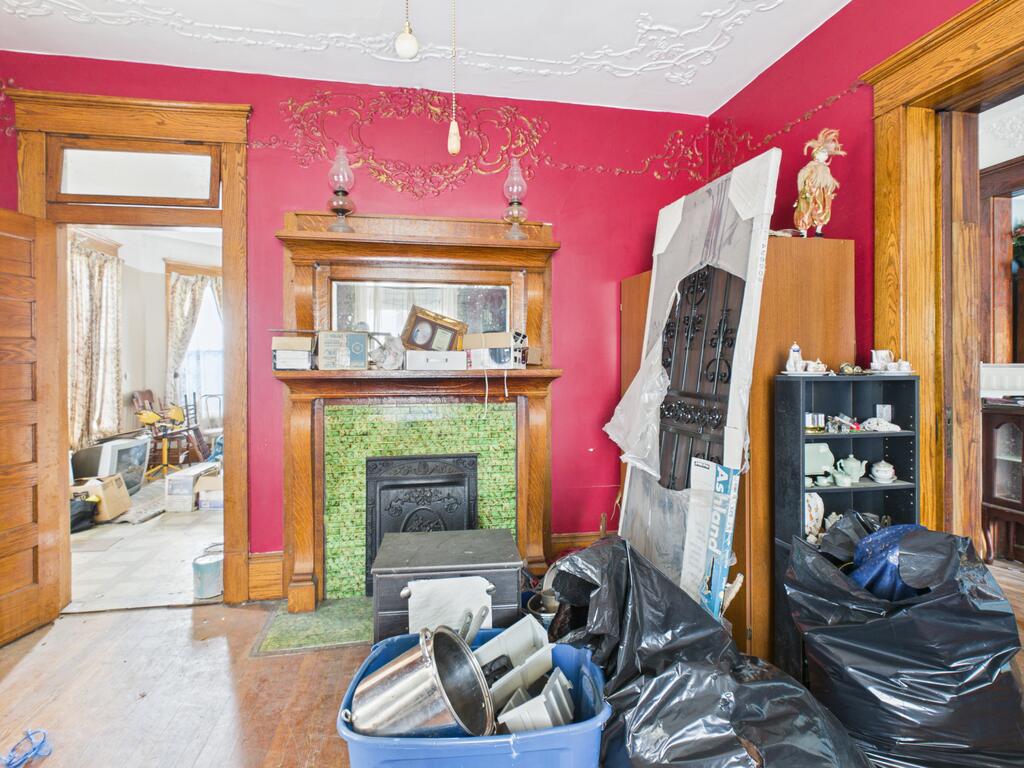 Interior room with ornate red walls, tiled fireplace, wood trim, and renovation clutter.