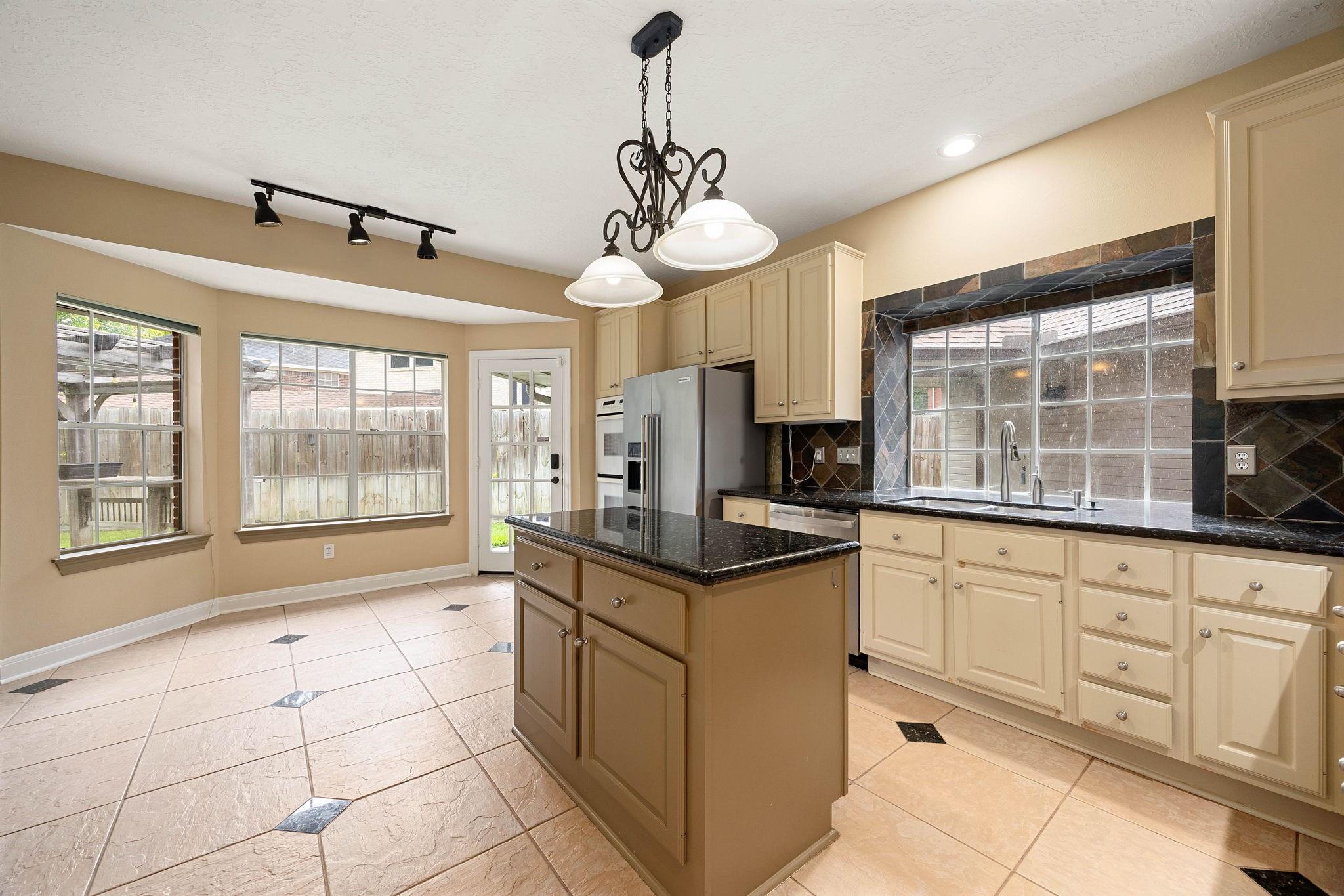 Kitchen with a central island, cream cabinets, dark countertops, and large windows.