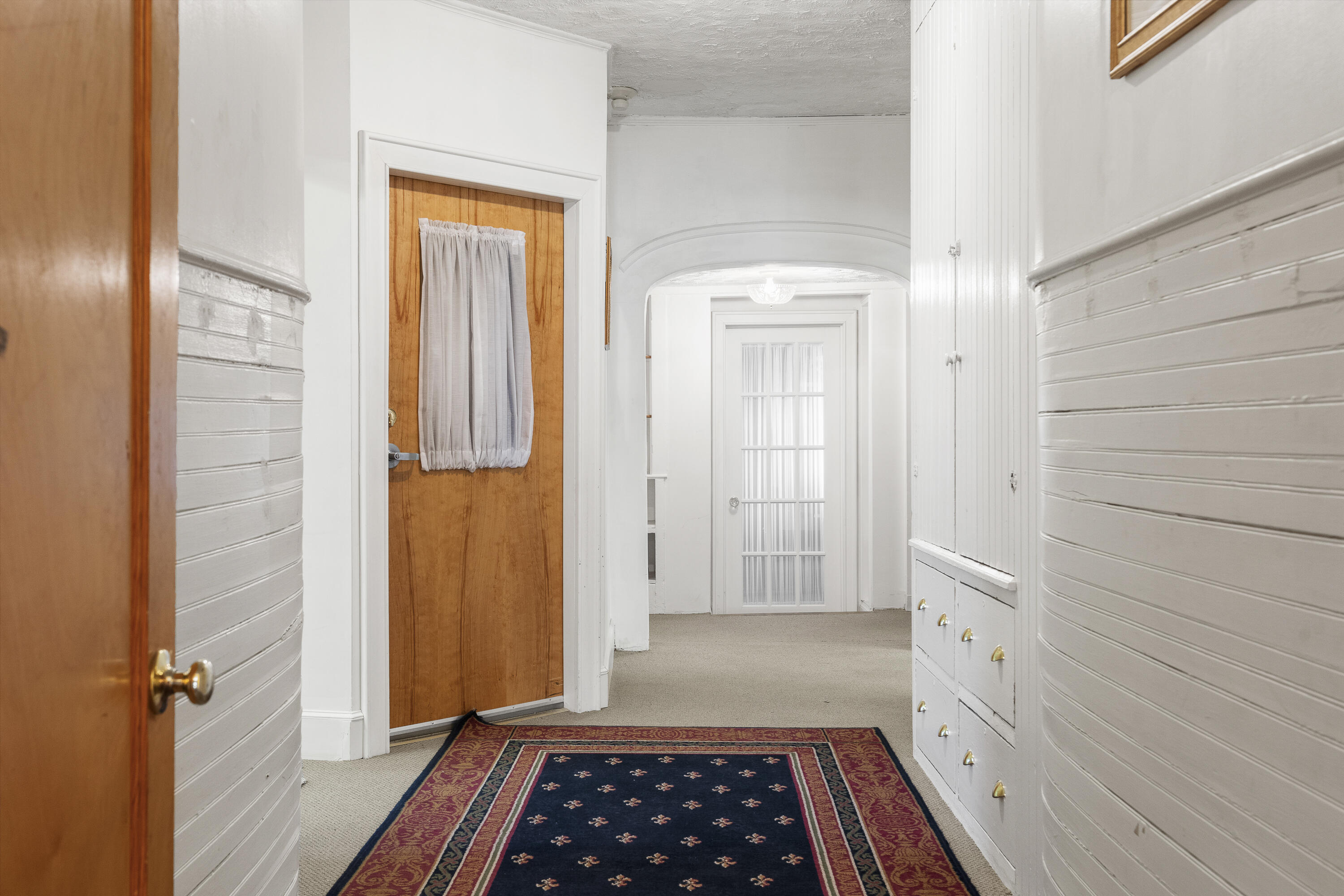 Interior hallway with an arched opening, built-in cabinetry, and a patterned runner rug.