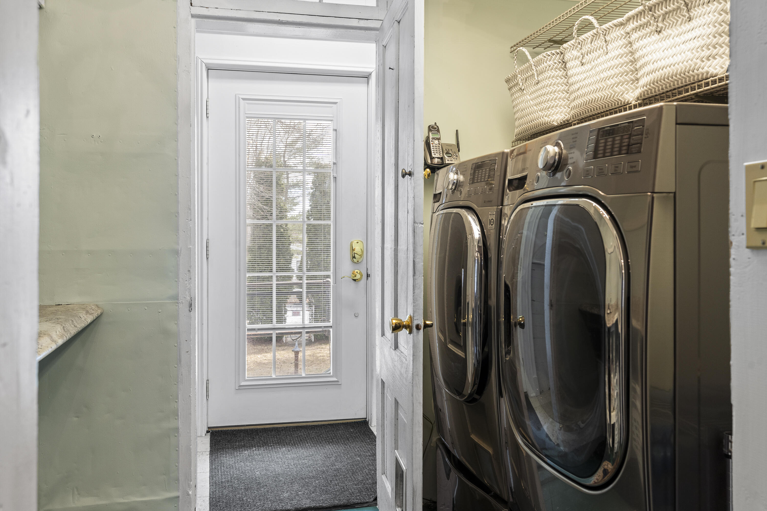 Laundry area with front-loading washer and dryer beside a white glass-paneled door.