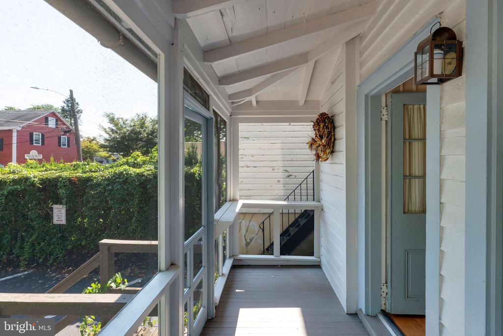 Covered porch with glass panels, a pale blue door, and stairs leading down.