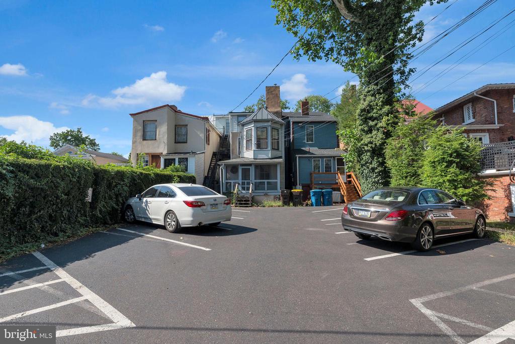 Multi-unit building behind a paved parking lot, with marked spaces and two parked cars.