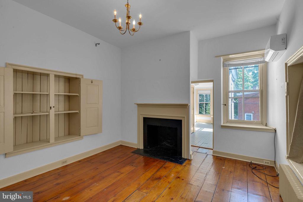 Unfurnished living room with a fireplace, built-in shelves, and polished hardwood floors.