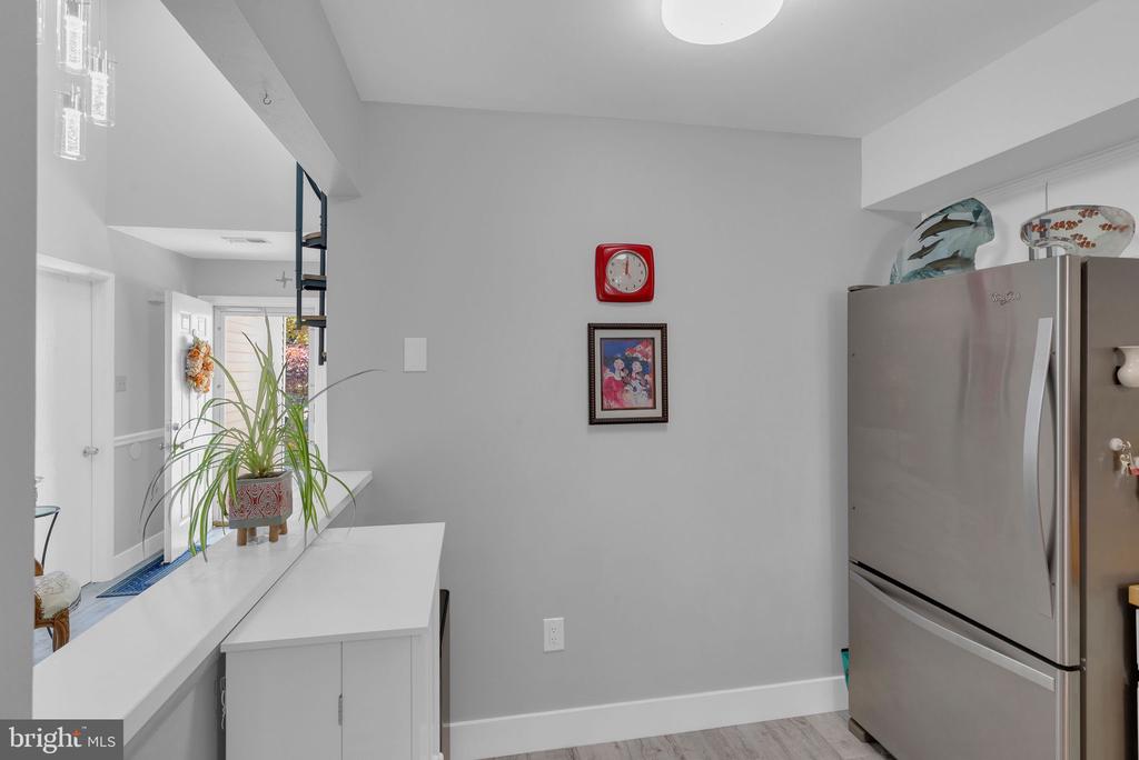 Kitchen with stainless steel refrigerator, white peninsula, and potted plant beside the entryway.