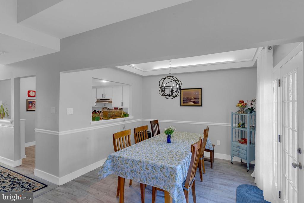 Dining room with a patterned tablecloth, globe chandelier, kitchen pass-through, and French doors.