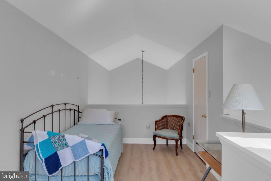 Bedroom with a metal-frame bed, blue-and-white quilt, and wooden chair.