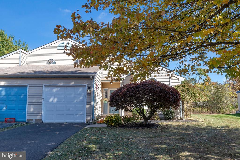 Home with an attached two-car garage, paved driveway, and burgundy ornamental tree in the front yard.