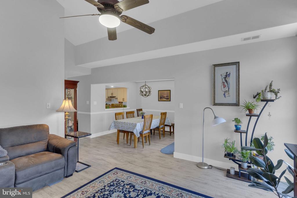 Open living and dining room with a gray sofa, dining set, and light wood-look flooring.