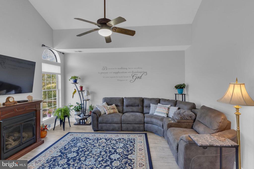 Living room with a gray sectional, blue patterned rug, fireplace, and tall arched window.