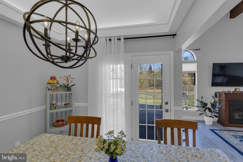 Dining area with an orb chandelier, floral tablecloth, and glass-paneled door to the yard.