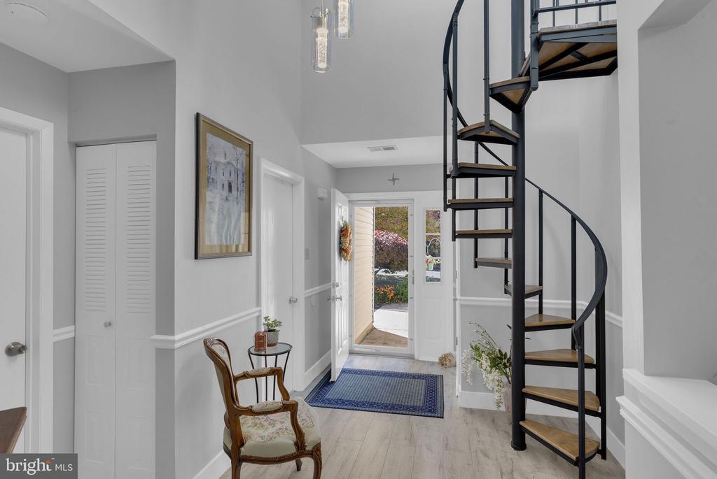 Entry foyer with a black spiral staircase, wood treads, and a glass-paneled front door.
