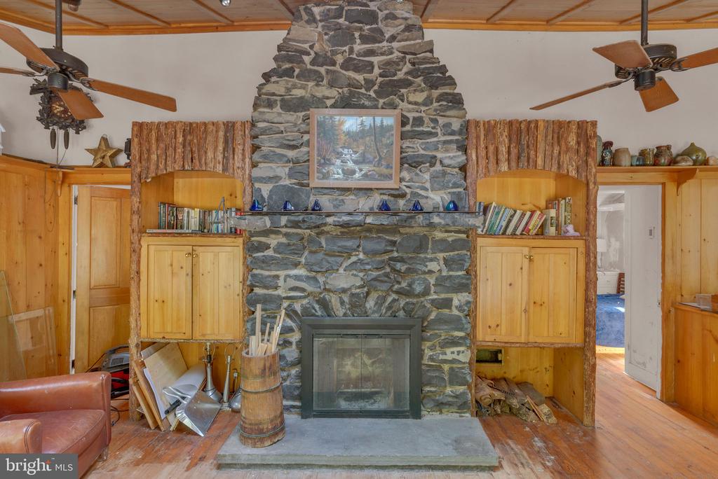 Living room with a floor-to-ceiling stone fireplace, wooden built-ins, and a vaulted wood ceiling.