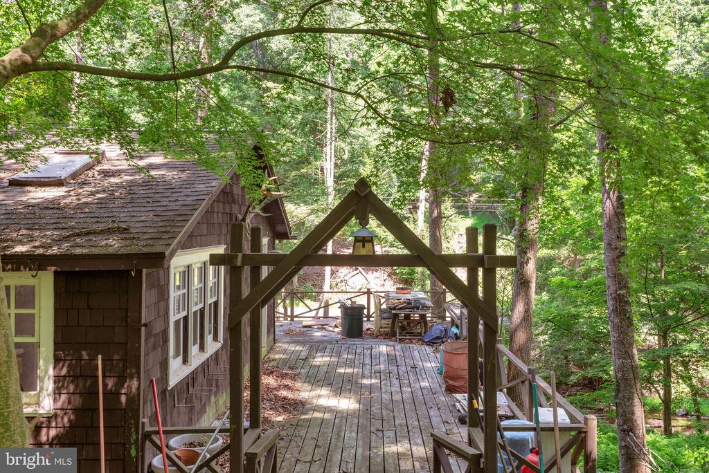 Wooden deck beside a shingle-sided cabin, surrounded by leafy trees.