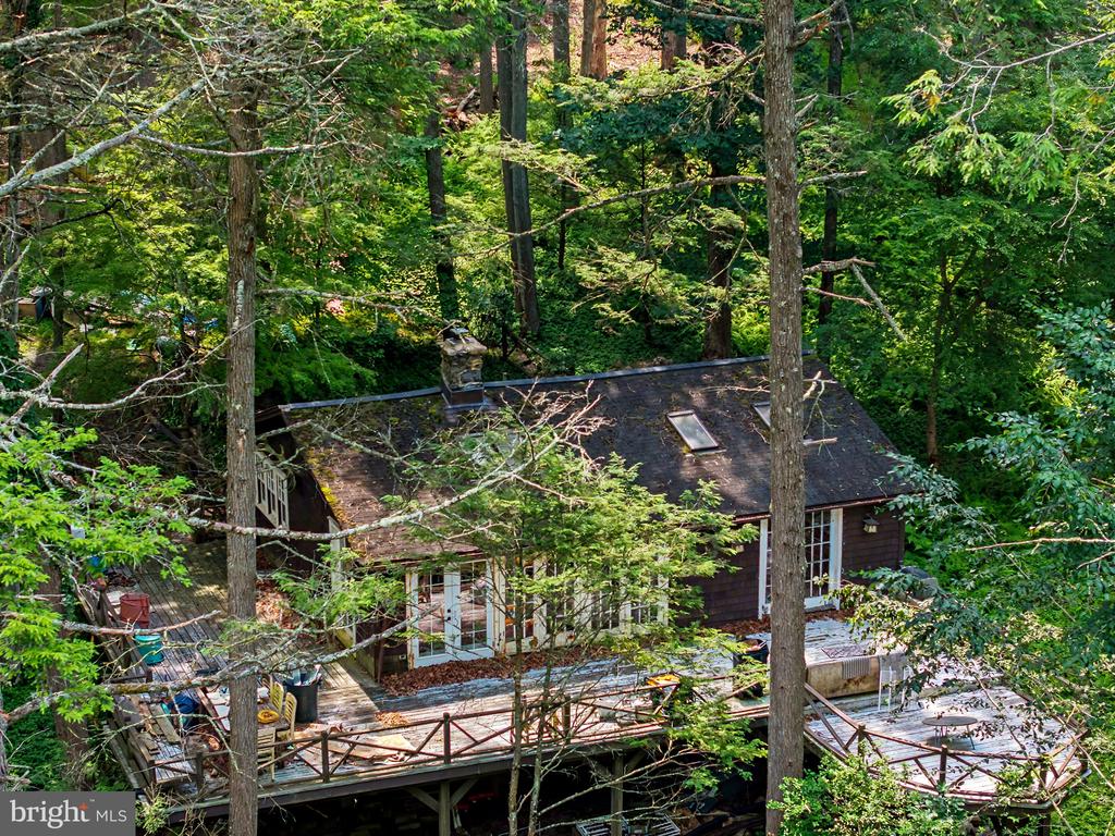 Woodland house with expansive wooden decks, seen from above among dense trees.