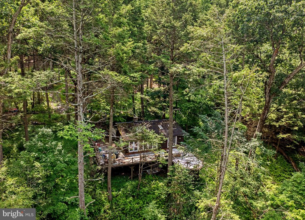 Aerial view of a wooded home with a large elevated deck.
