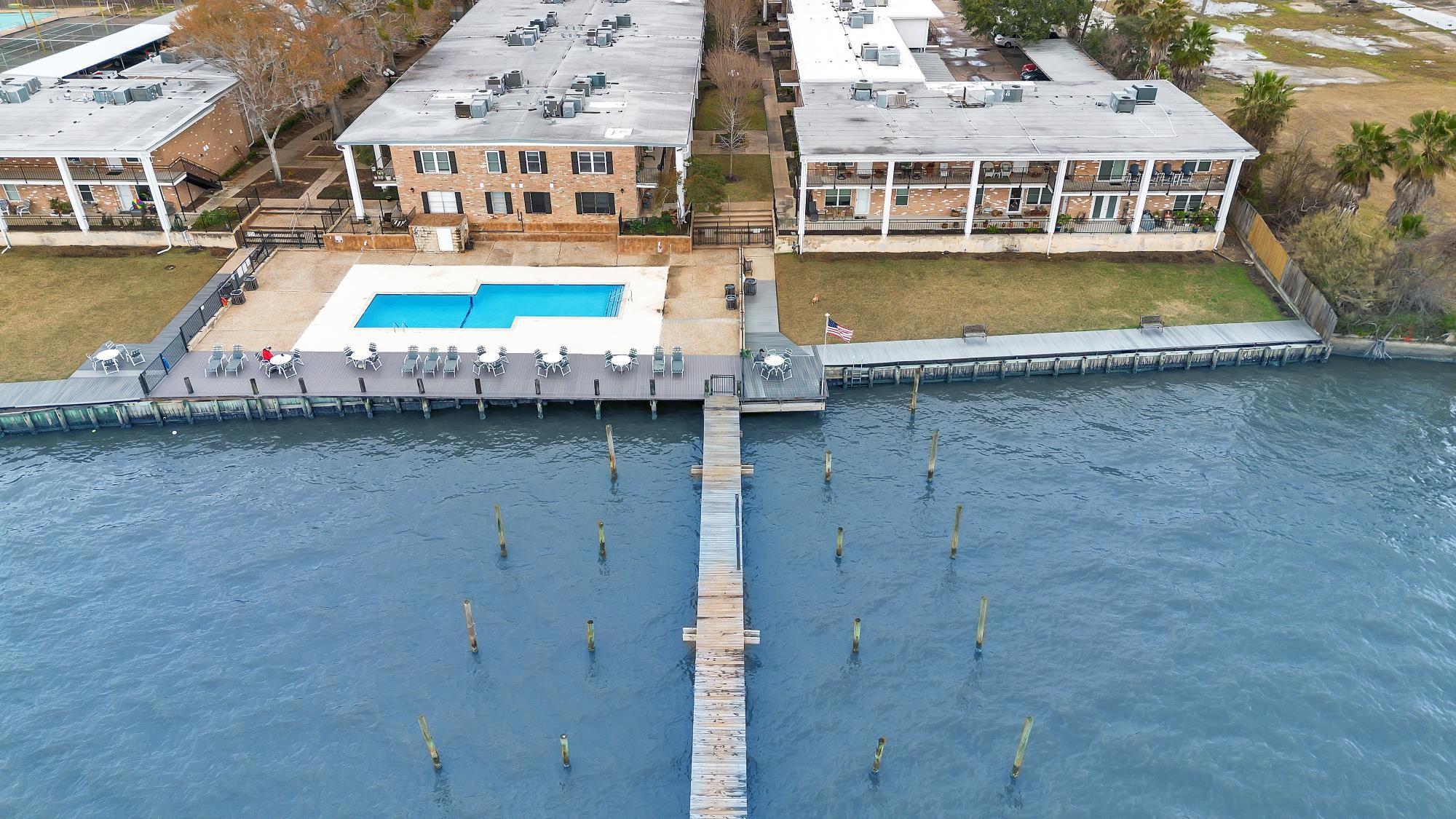 Waterfront residential complex with a pool, dock, and deck beside the water.