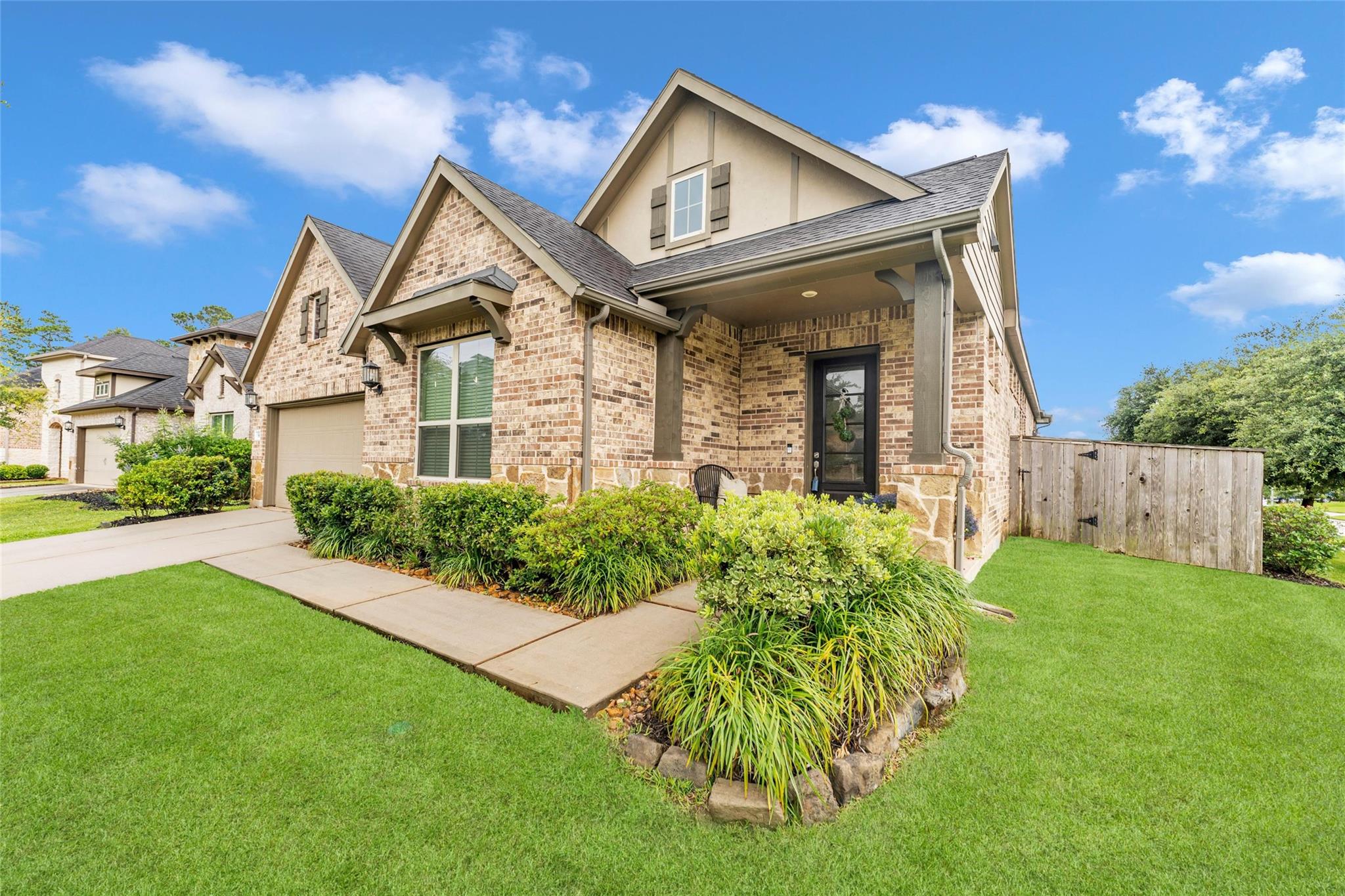 Brick home with a covered entry, attached garage, and landscaped front lawn.
