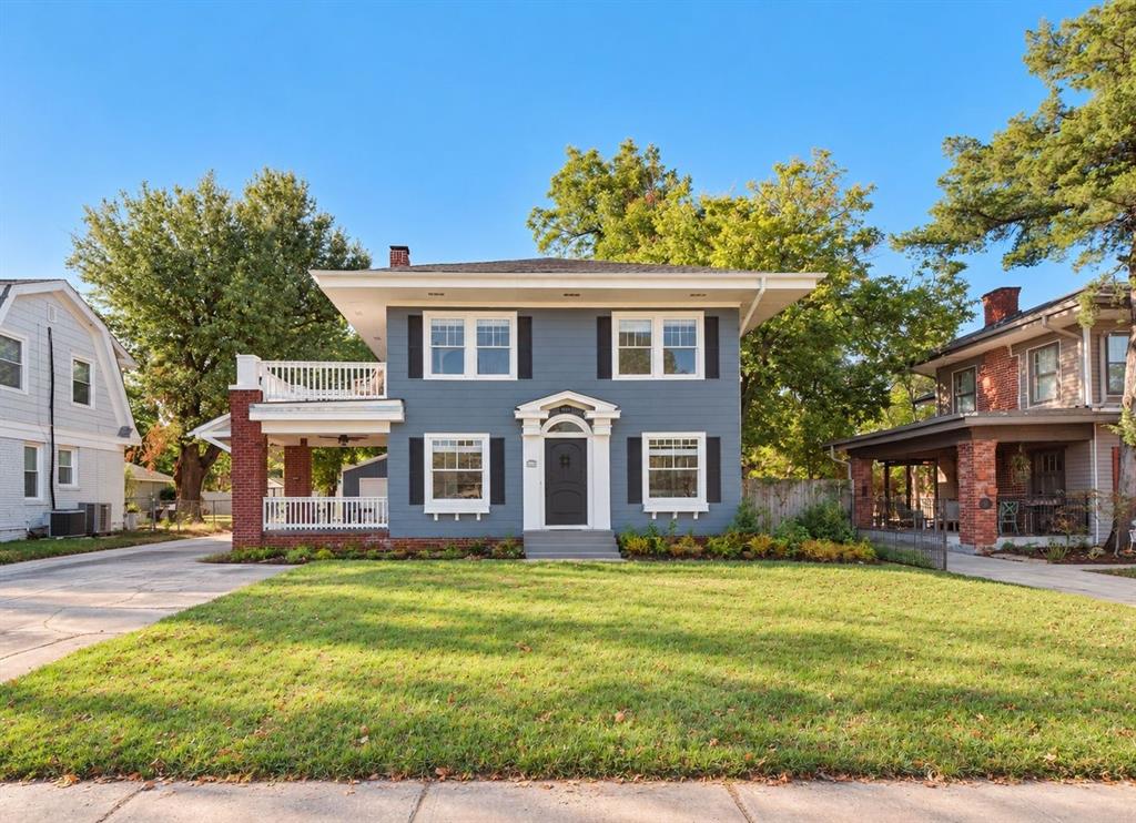 Two-story blue house with white trim, a covered porch, and a broad front lawn.