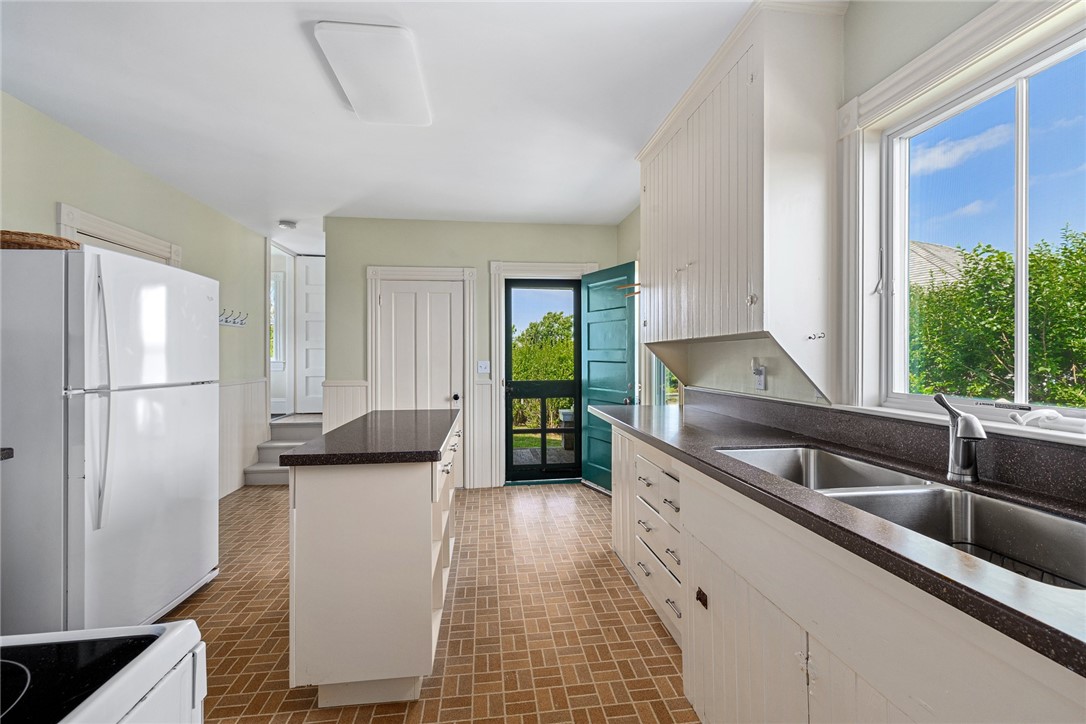 Kitchen with white cabinets, dark counters, a central island, and a large window overlooking greenery.