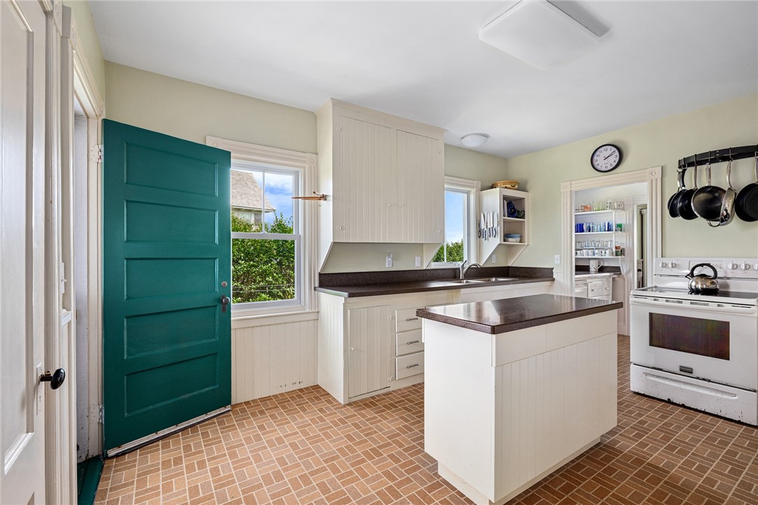 Kitchen with a central island, brick-patterned floor, and teal door.