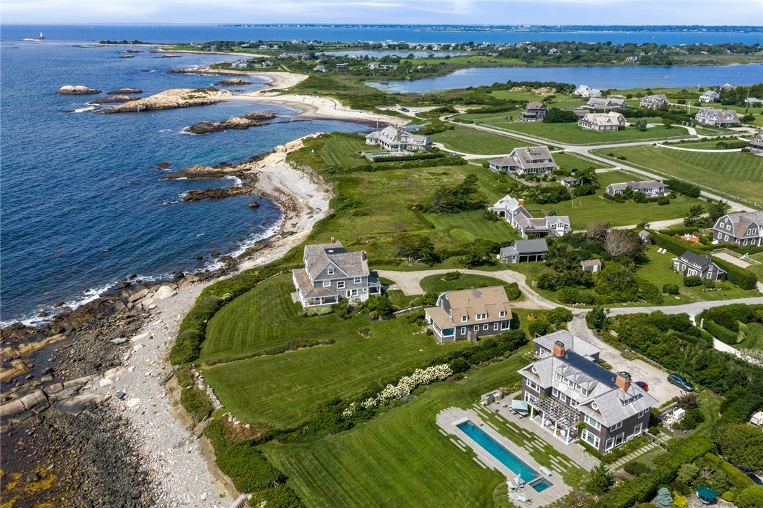 Aerial view of a coastal home with a swimming pool beside a rocky shoreline.