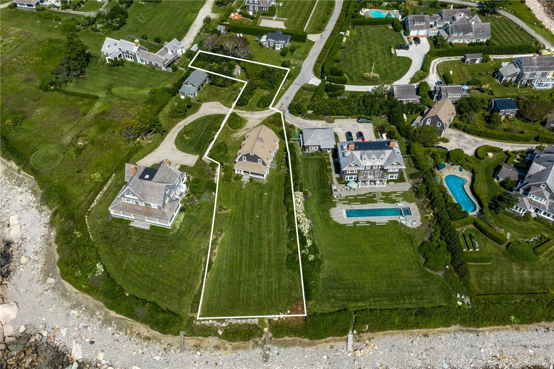Aerial view of a coastal property outlined in white, extending from a home to a rocky shoreline.