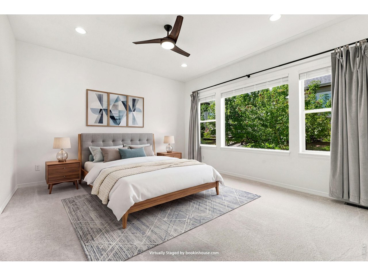 Virtually staged bedroom with a wood-framed bed, large windows, and a dark-bladed ceiling fan.