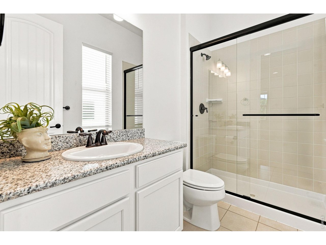 Bathroom with a speckled granite vanity and a large glass-enclosed tiled shower.