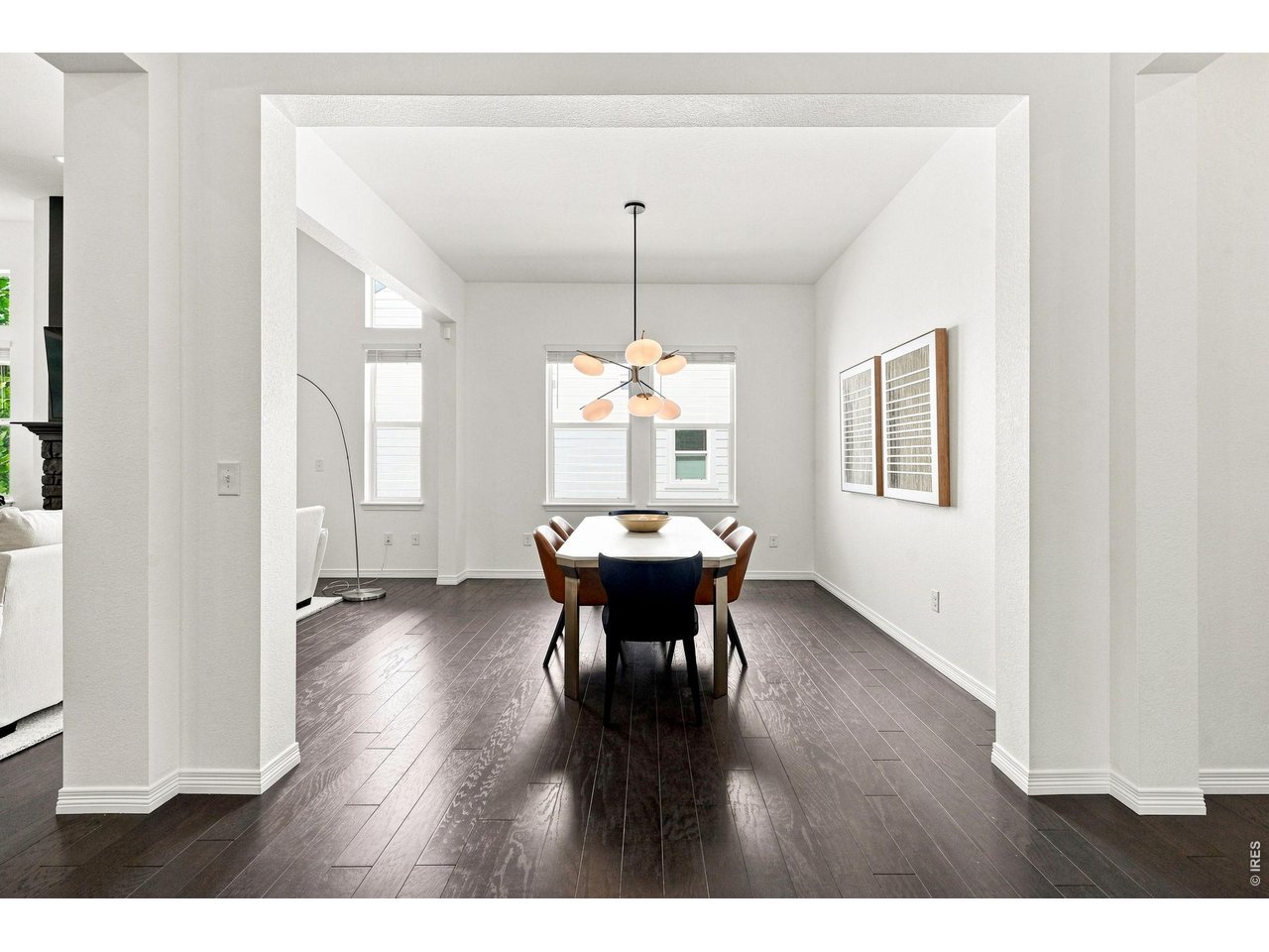 Dining room with a modern pendant chandelier, tall windows, and dark hardwood floors.