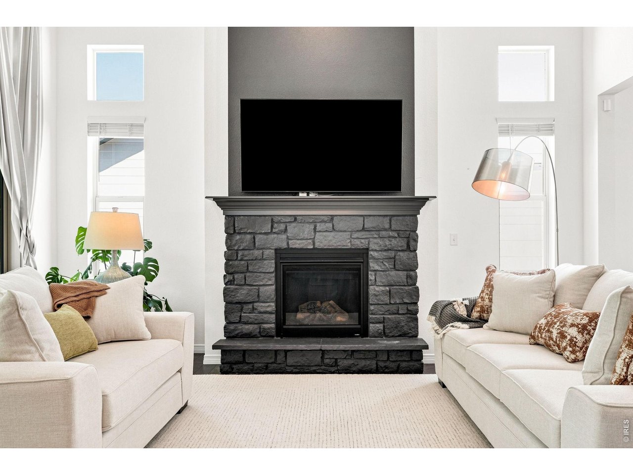 Living room with cream sofas and a dark stone fireplace beneath a television.