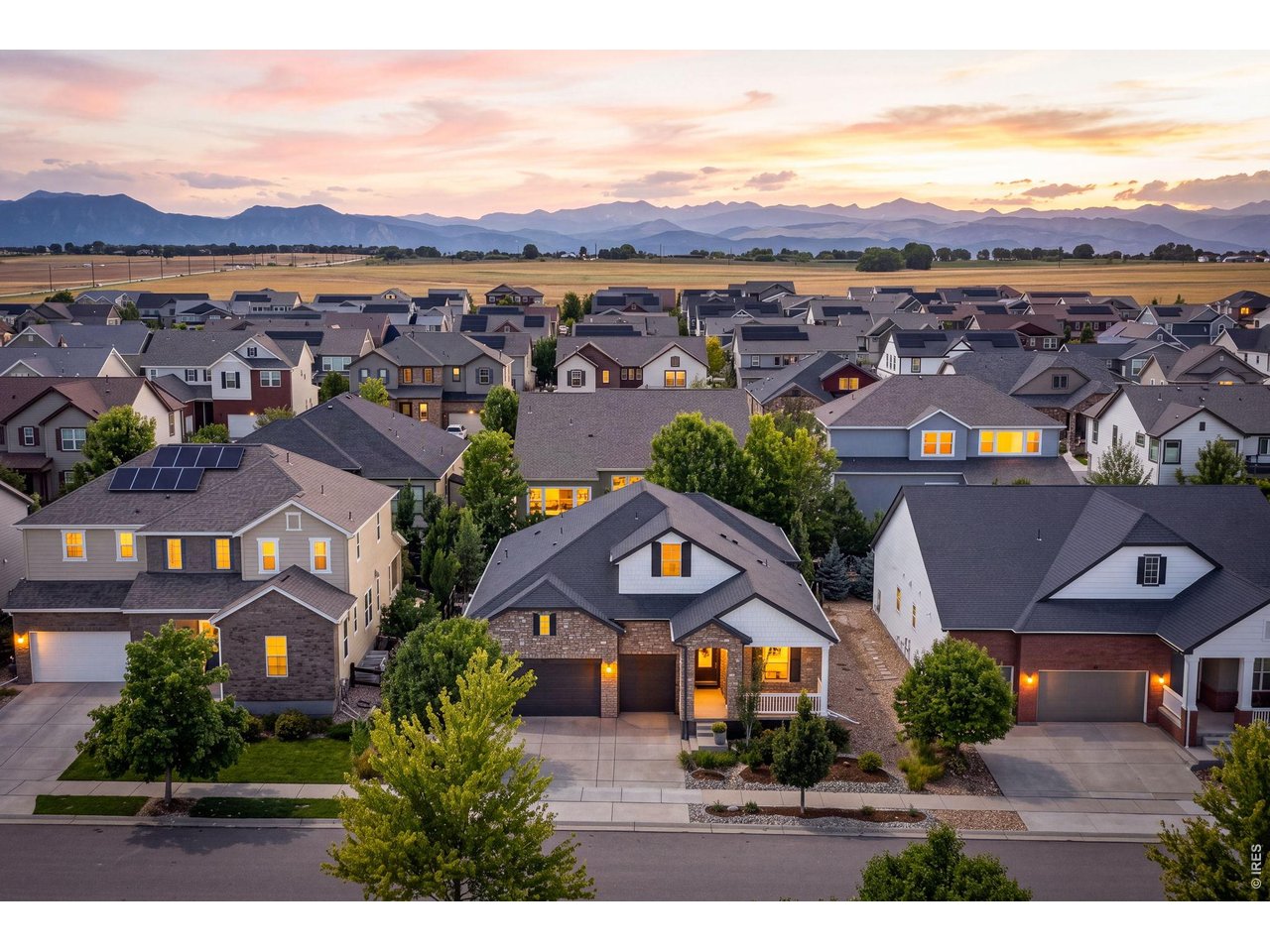 Suburban homes at dusk with the mountains in the distance and a stone-fronted house in the foreground.
