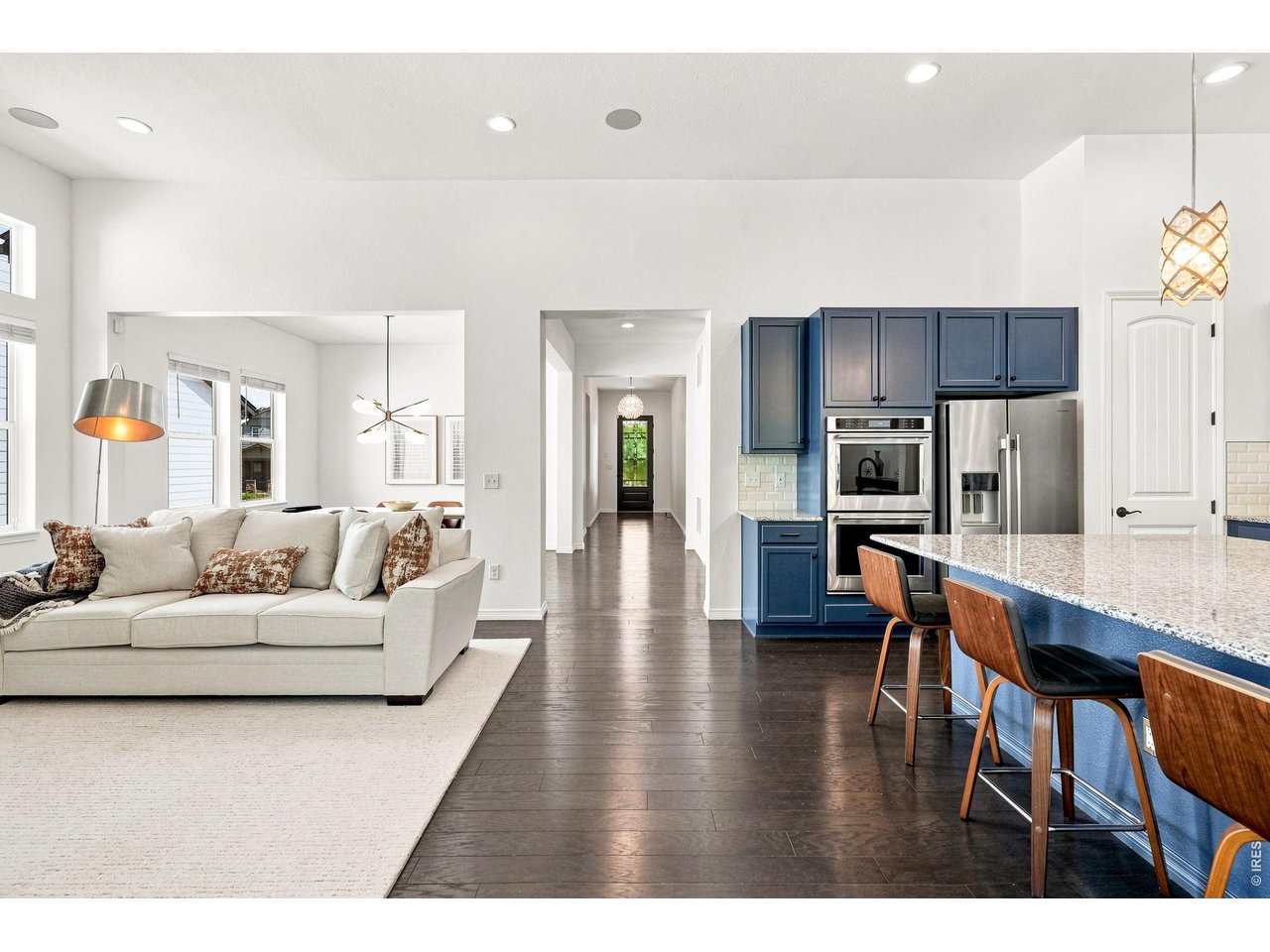 Open-plan living room and kitchen with navy cabinets, a granite island, and a white sofa.